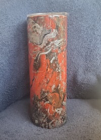 a tumbler with an orange and black marble design